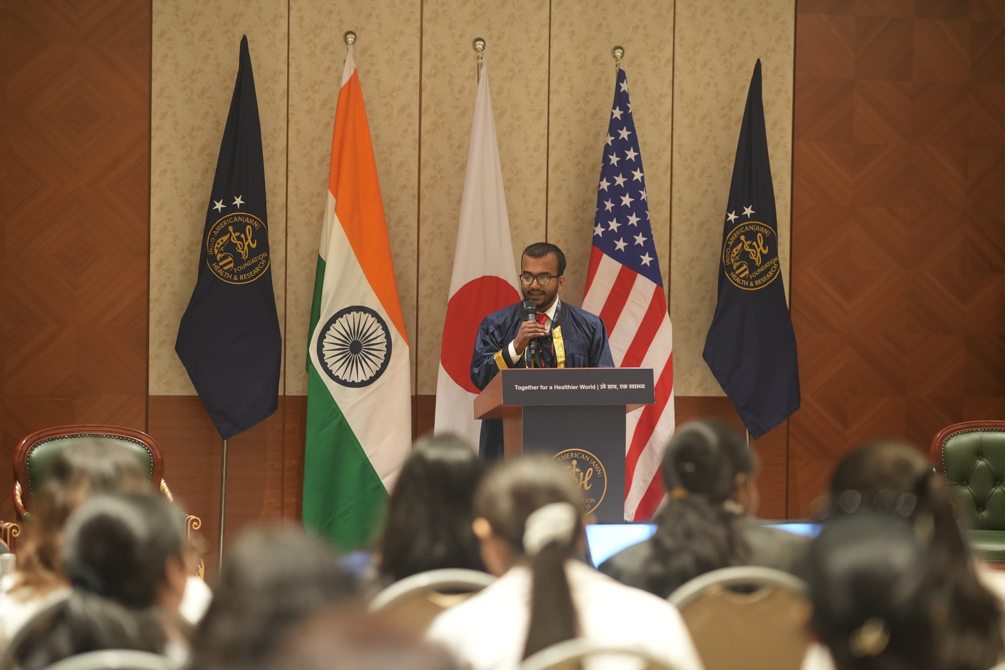 Jabez David John receiving Gold Honours and addressing dignitaries at Bharat Mandapam, New Delhi, beneath the Indian and American flags